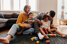 family sits in the living room of their house. 