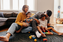 family sits in the living room of their house.