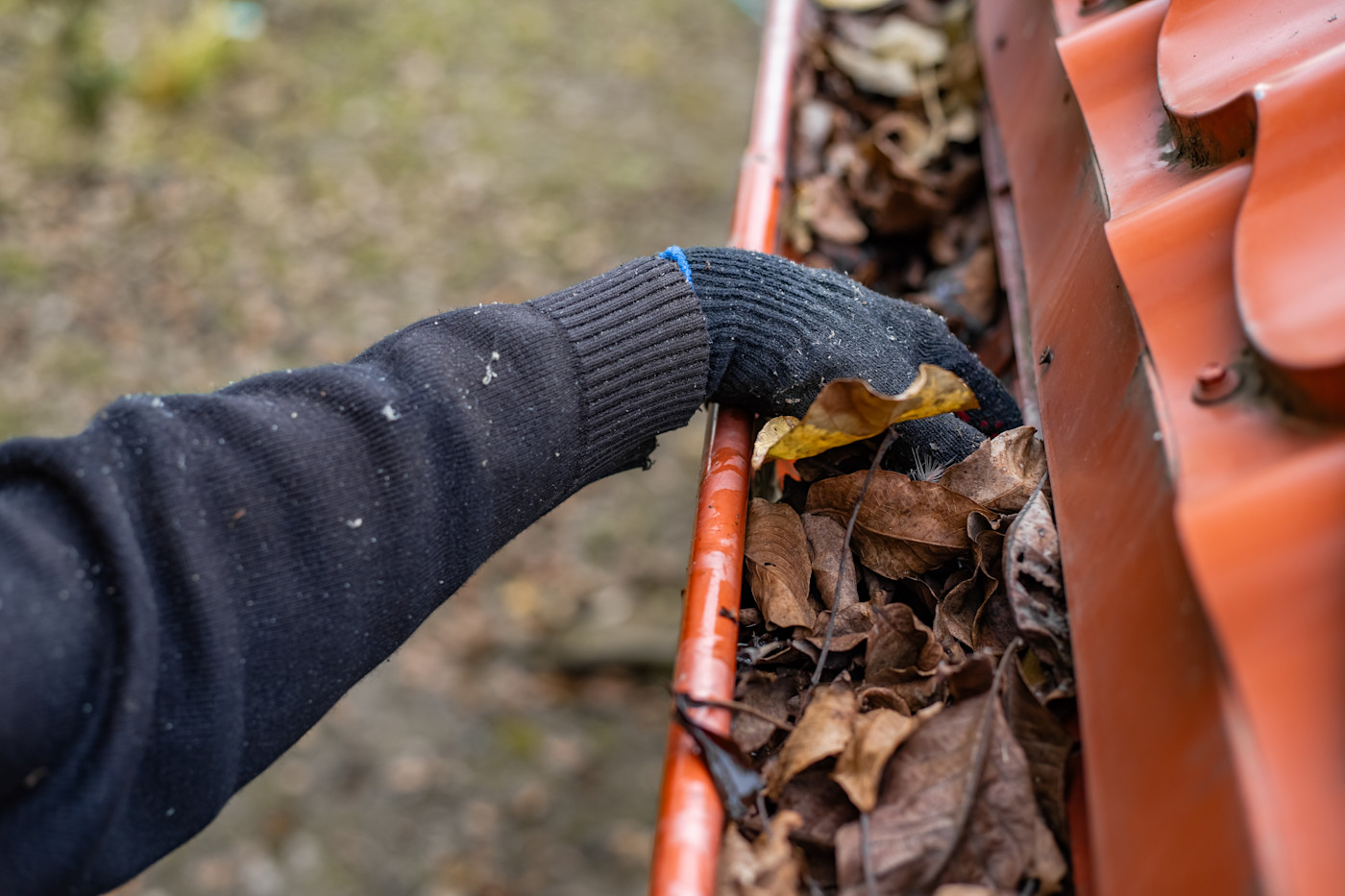 A tradesperson is clearing out a blocked gutter.