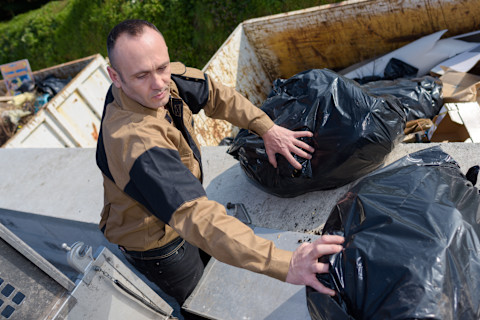 A builder is sorting out a skip