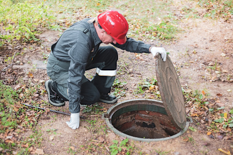 An image showing a partially excavated septic tank being repaired, with tools and equipment visible around the site, highlighting the process of fixing and maintaining a septic system