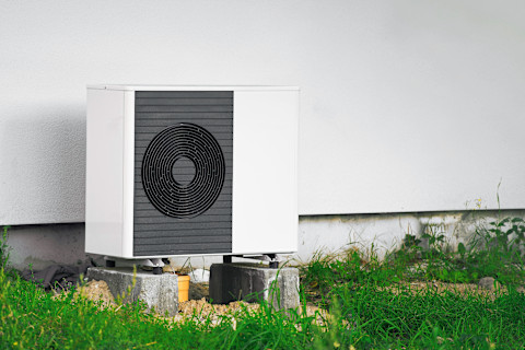 A ground source heat pump unit installed outdoors on a green lawn, featuring modern equipment for sustainable energy and efficient heating.