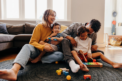 family sits in the living room of their house.