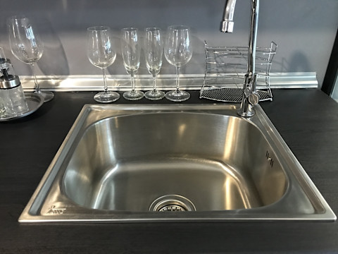 A stylish bar sink with a modern faucet installed in a sleek countertop, featuring a small, undermount design suitable for a home bar setup.