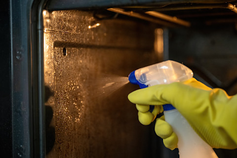 A cleaner is cleaning an oven.