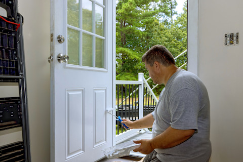 Person painting door with a roller