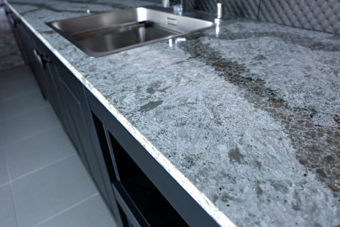 Beautiful quartz stone worktop on wooden kitchen cabinet with appliances and sanitary.