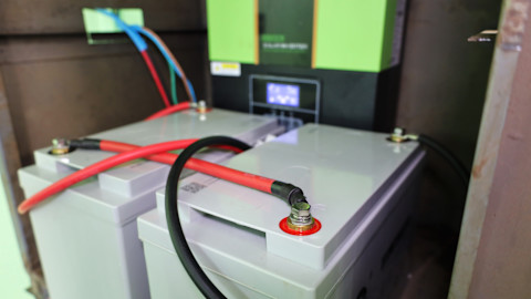 This image shows a grey plastic solar powered battery with red and black wires feeding out from the top panel.