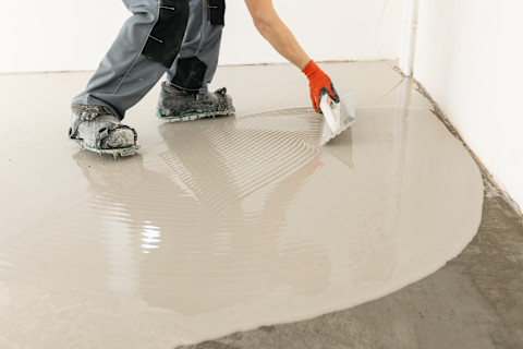 A tradesperson is updating the floor of a garage conversion