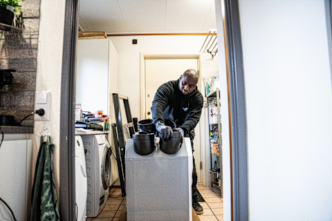A whole house dehumidifier unit installed in a basement or utility room, showing its large, box-like design and connected ductwork or vents.