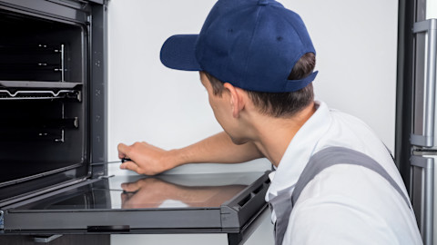 A tradesperson is checking over an oven repair.