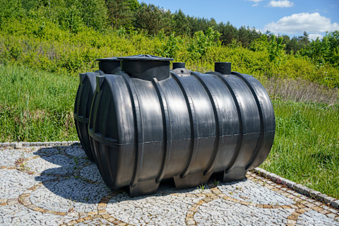 Two plastic septic tanks designed for domestic sewage treatment, placed side by side on a construction site.
