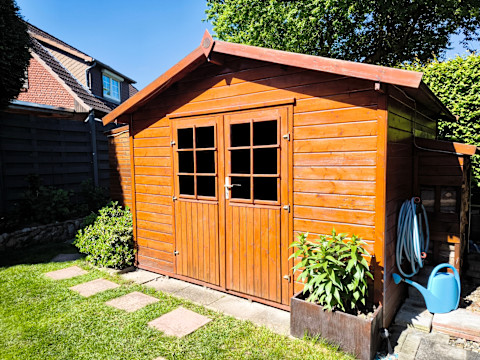 Side view of wooden garden shed glossed in teak color