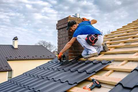 A man sitting on a roof with tiles for repair.