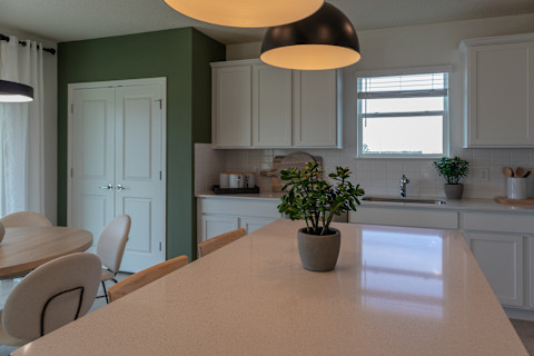 A kitchen island with a plant on it in a country-style white kitchen.