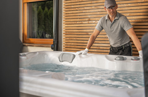 An electrician standing next to a hot tub which he has installed.