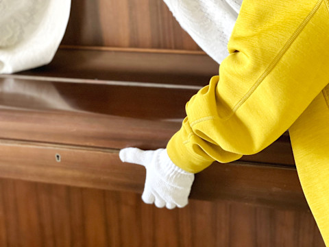 This image shows removal people moving a piano. The fallboard is closed and they are wearing gloves to prevent damage.