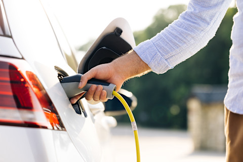 The driver of the electric car inserts the electrical connector to charge the batteries.