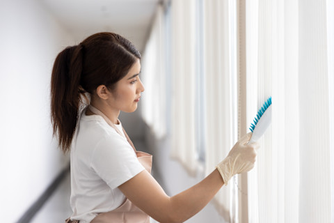 A cleaner is attending to vertical blinds