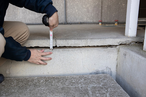 Cracked building foundations being measured