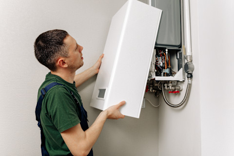 This image shows a central heating engineer fixing a boiler to a wall.