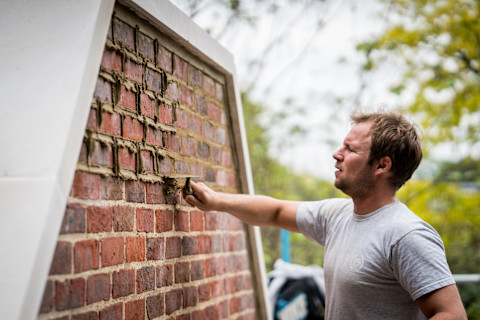 A stonemason cladding a stone wall.