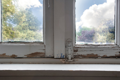 The photo shows a decaying wooden window frame with deep cracks, flaky brown wood, and white fungal growth, clearly indicating dry rot damage.
