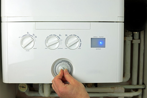 A male hand adjusting a dial on a whitehome combi boiler