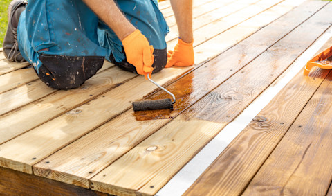A man is varnishing a new wooden deck