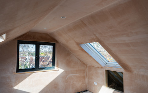 Brown plastered walls in the property, preparation for the paint. Loft conversion with roof windows selective focus