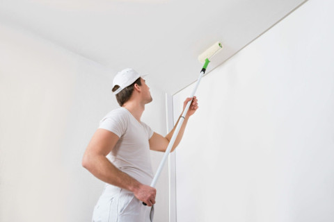 A man is plastering a ceiling.