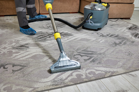 A professional carpet cleaner is using a specialised machine to refresh a rug.