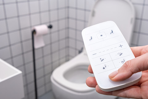 remote Control with buttons of the smart toilet bowl in the background