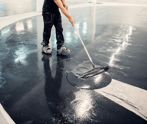 Workplace under maintenance, Epoxy floor installation over existing concrete using roller and rubber spatula