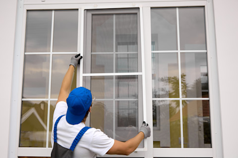 A man installs a new pane of glass in a window.