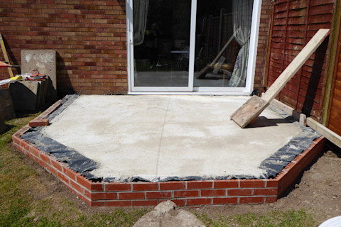 close up of concrete and brick foundation for conservatory base for house extension in garden with patio doors summer sun