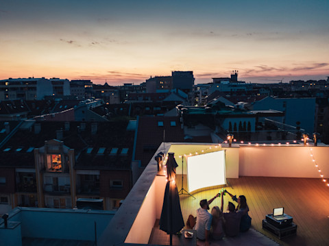 An outdoor cinema set up on a rooftop with friends watching