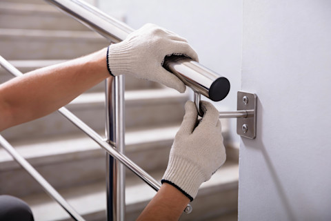 This image shows a hand installing a metal handrail. 