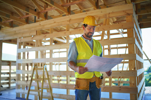 A large house structure made of wooden beams and chipboard, used as an early stage of building a house