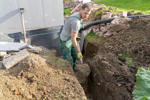 Groundworker installing a French drain system in a property's garden