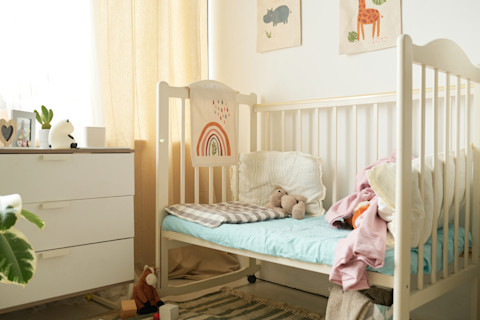 A nursery room with a bed and side table.