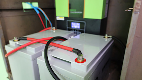 This image shows a grey plastic solar powered battery with red and black wires feeding out from the top panel.