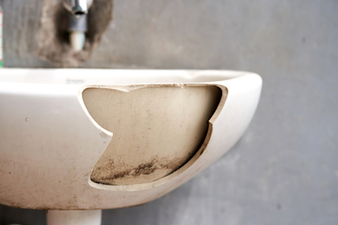 This image shows a ceramic sink with a large portion of ceramic missing from the basin.