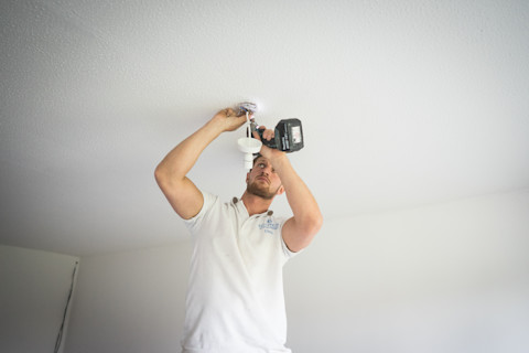 An electrician fixing a dimmer switch on the wall