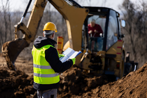 A builder uses a power drill to drill into a new structural feature for a house under construction