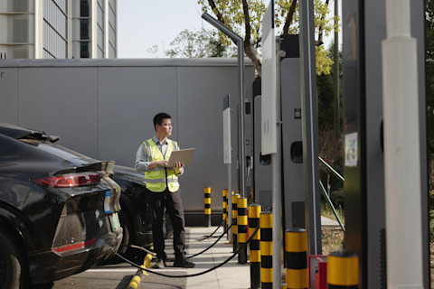 A technician is examining a public EV car charging port.