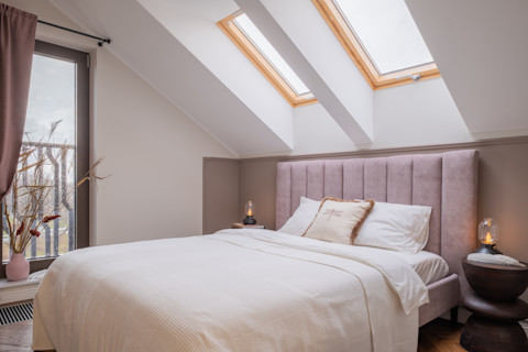 The image shows a cozy bedroom with a soft, neutral color palette. 