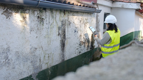 A tradesperson is carrying out a damp survey on a house affected by damp.