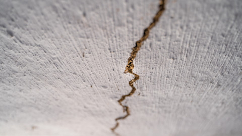 This image is a close-up of a cracked white clay ceiling inside a house, showing detailed texture and damage.