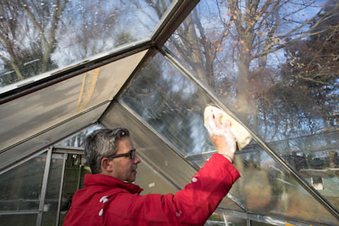 A conservatory installer wearing a red jacket cleaning a conservatory.